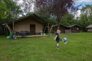een jonge jongen die met een voetbal speelt voor een tent bij Camping Leef! in Melderslo