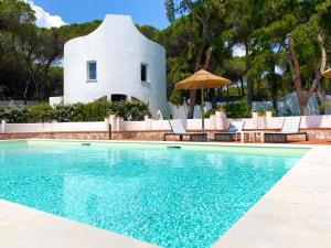 a swimming pool in front of a white house at Hotel Mare Pineta in Santa Margherita di Pula