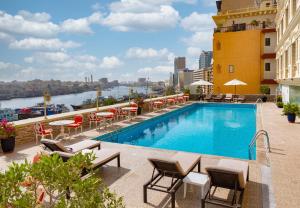 a pool on the roof of a building with tables and chairs at Carlton Tower Hotel in Dubai