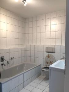 a white bathroom with a tub and a toilet at Lotus Apartment in Fichtenberg