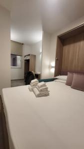 a bedroom with a large white bed with towels on it at A Nanein con Joy in Bologna