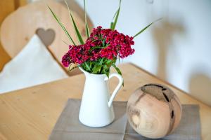 eine weiße Vase mit roten Blumen auf dem Tisch in der Unterkunft Zunerhof Studio Fenn in Lengstein