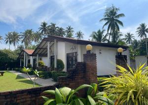 mały biały dom z palmami w tle w obiekcie Sanda Eliya Resort w mieście Bentota