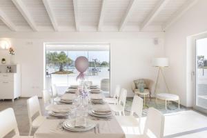 biała jadalnia z długim stołem i białymi krzesłami w obiekcie Hotel S'arena Beach w mieście La Caletta