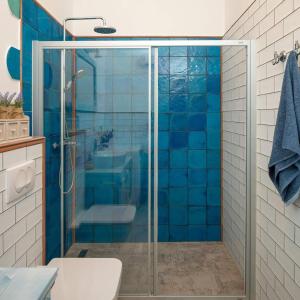 a bathroom with a glass shower with blue tiles at Luxury seafront Villa Lighthouse Ligero on Host island - Vis island in Vis