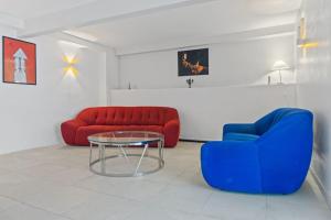 ein Wohnzimmer mit zwei roten und blauen Stühlen und einem Glastisch in der Unterkunft Maison Bernabet - Rooftop avec vue sur la Montagne Pelée in Saint-Pierre