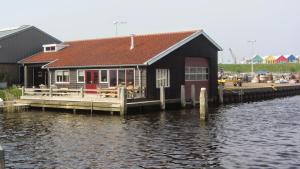 a building on a dock next to a body of water at Boothuis Lauwersoog in Lauwersoog