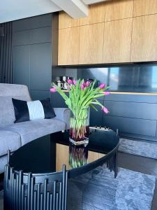 - un salon avec un vase de fleurs sur une table dans l'établissement Baltic Riviera Apartments - Granaria Sauna Apartment, à Gdańsk