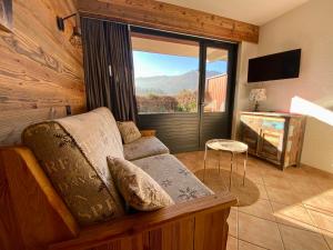 a living room with a couch and a large window at Studio 2/4 personnes - Centre village in La Clusaz