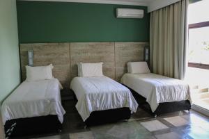2 camas en una habitación con una pared verde en ARAGUAIA HOTEL, en Barra do Garças