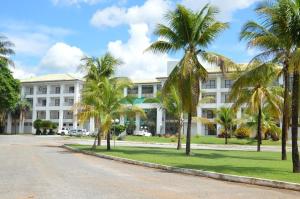 a large white building with palm trees in front of it at ARAGUAIA HOTEL in Barra do Garças