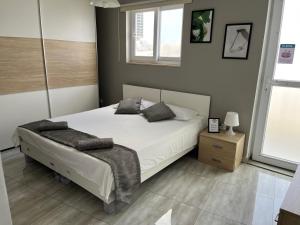 a bedroom with a white bed and a window at F5-1 Double room with private bathroom and balcony in shared Flat in Msida