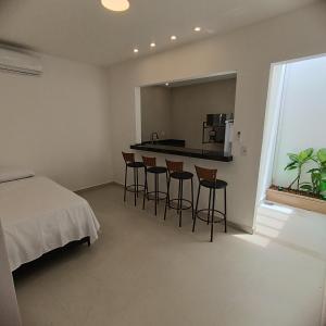 1 dormitorio con 1 cama y cocina con taburetes en Ressurgência loft, en Arraial do Cabo
