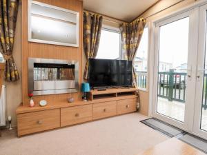 a living room with a television on a wooden entertainment center at 12 Broughton Park - Sanctuary in Morecambe