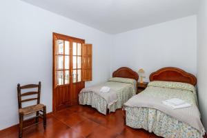 Cette chambre comprend 2 lits et une chaise. dans l'établissement Casa Lucia, à Periana