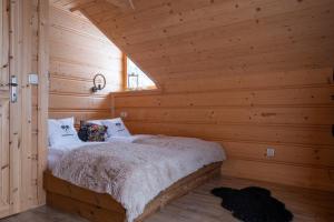 um quarto com uma cama num chalé de madeira em Legenda Lasu - drewniany domek w górach, przy stoku narciarskim Kotelnica, Białka Tatrzańska, w pobliżu Term Bania em Groń