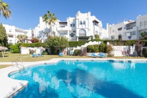 a swimming pool in front of a large white building at El Zoco de Iñaki - Adults Only in Sitio de Calahonda