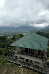 budynek z zielonym dachem na wzgórzu w obiekcie My Kingdom Munnar w mieście Munnar