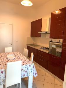 uma cozinha com uma mesa com cadeiras brancas e um fogão em Una finestra sul mare em Savona