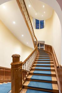 un escalier en colimaçon avec des balustrades en bois et un tapis bleu dans l'établissement Villa Thea Hotel am Rosengarten, à Bad Kissingen