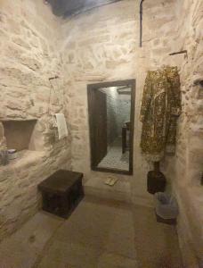 a stone bathroom with a mirror and a stool at نزل كوفان التراثي Koofan Heritage Lodge in Salalah