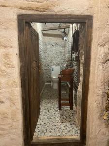 a bathroom with a toilet and a wooden door at نزل كوفان التراثي Koofan Heritage Lodge in Salalah