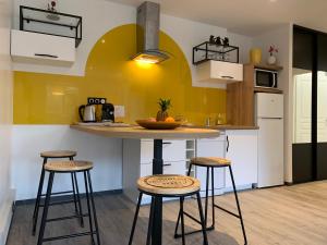 a kitchen with three bar stools and a yellow wall at L'Étoile de Mer - Étretat in Le Havre