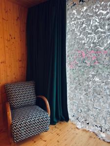 a chair sitting in front of a window with a curtain at Luciz’ in Hunawihr