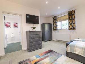 a bedroom with a bed and a television on the wall at Maples Annex in Heanor