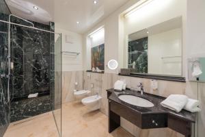 La salle de bains est pourvue d'un lavabo, d'une douche et de toilettes. dans l'établissement Villa Thea Hotel am Rosengarten, à Bad Kissingen