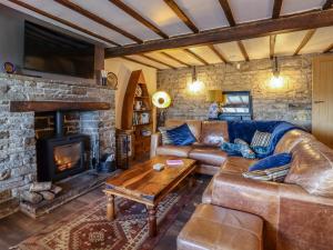 a living room with a leather couch and a fireplace at Wells Cottage in Holmfirth