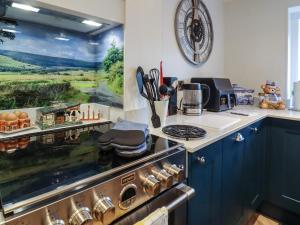 a kitchen with a stove and a painting on the wall at Wells Cottage in Holmfirth