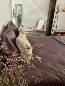 a bedroom with a bed with pillows and a chair at Studio spacieux proche gare et centre ville in Saint-Amand-les-Eaux