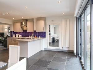 a kitchen with white cabinets and a large window at 7 The Village in Ilkeston