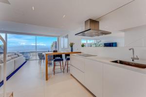 a kitchen with white cabinets and a table with chairs at Luxury triplex + pool, jacuzzi - SissiPark Azul in Acantilado de los Gigantes