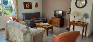 ein Wohnzimmer mit einem Sofa und einem TV in der Unterkunft Villa des Oliviers in Fontvieille