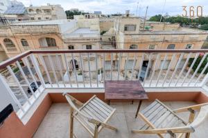a balcony with two chairs and a wooden table at A beautiful spacious home in a picaresque location by 360 Estates in Hal Ghaxiak +35 photos