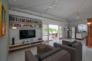 een woonkamer met een tv en een bank en stoelen bij Piscadera Bay Resort 24 in Willemstad