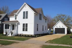 uma casa branca com garagem em Restored Queen Anne Cottage em Maquoketa