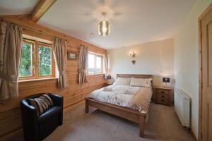 a bedroom with a bed and a chair in it at Beech Tree Eco Lodge in Brecon