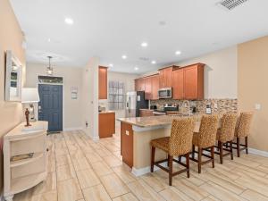 an open kitchen with wooden cabinets and bar stools at Villa at Champions Gate Resort in Orlando near Theme Parks with Private Pool, SPA & Movie Theater in Davenport