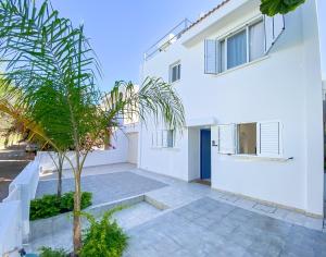 a white house with a palm tree in the courtyard at Phaedrus Living Azure Serenity Villa in Khlorakas
