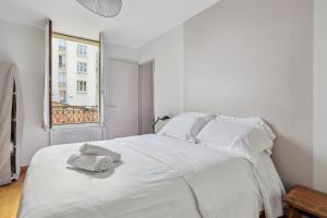 ein weißes Schlafzimmer mit einem Bett mit Handtüchern darauf in der Unterkunft Hôtel Robespierre Ex Idéal hôtel Paris - Montreuil in Montreuil