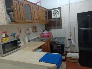 La cuisine est équipée de placards en bois et d'un four avec plaques de cuisson. dans l'établissement شقة فندقية علي البحر مباشرة بجليم, à Alexandrie