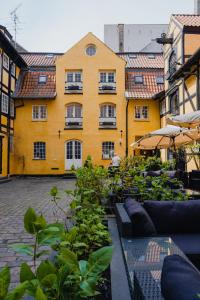 un edificio amarillo con un montón de plantas delante de él en Capsule Hotel Nyhavn63, en Copenhague