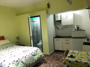 a small bedroom with a bed and a kitchen at Monoambiente en km3 in Comodoro Rivadavia