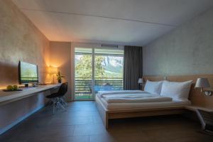 una camera d'albergo con un letto, una scrivania e una finestra di Hotel des Alpes a Flims Altre 37 foto