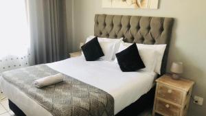a bedroom with a large bed with white sheets and black pillows at @Menlyn Place, Menlyn Maine, Pretoria - Accommodation in Pretoria