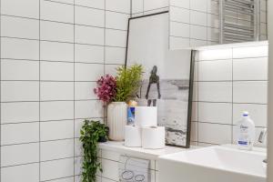 a white tiled bathroom with a sink and a mirror at 1 Bed Executive Apartment near Kings Cross & Camden FREE WIFI by City Stay Aparts London in London