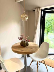 een tafel met twee witte stoelen en een vaas met bloemen bij Duynbossie in Schoorl